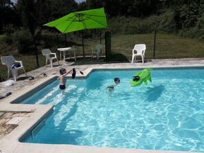 A swimming pool with inflatable toys, chairs, and a green umbrella. - Gîte Goulet for 5 people, just a stone's throw from Suisse Normande! (fresné-la-mère)
