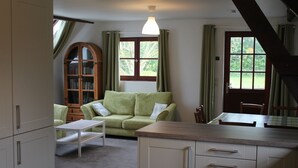 Ein gemütliches Wohnzimmer mit einem grünen Sofa, einer Holzkommode und einem Esstisch.
