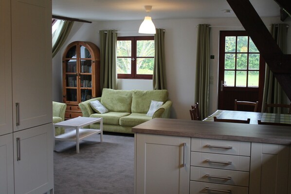 A cozy living room with a green sofa, a wooden cabinet, and a dining table.