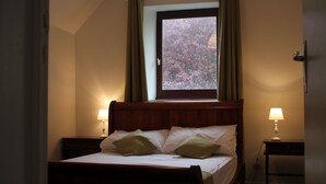 Ein Schlafzimmer mit einem Bett, zwei Nachttischlampen, einem Fenster mit Vorhängen und einem Nachttisch.
