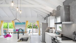 Una cocina moderna con una isla central, electrodomésticos de acero inoxidable y vistas al exterior.