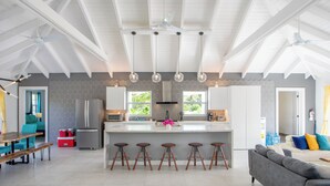 Una cocina amplia con una isla central, taburetes de bar y un diseño de techo moderno.