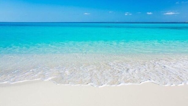 Una playa con agua turquesa cristalina y arena blanca.