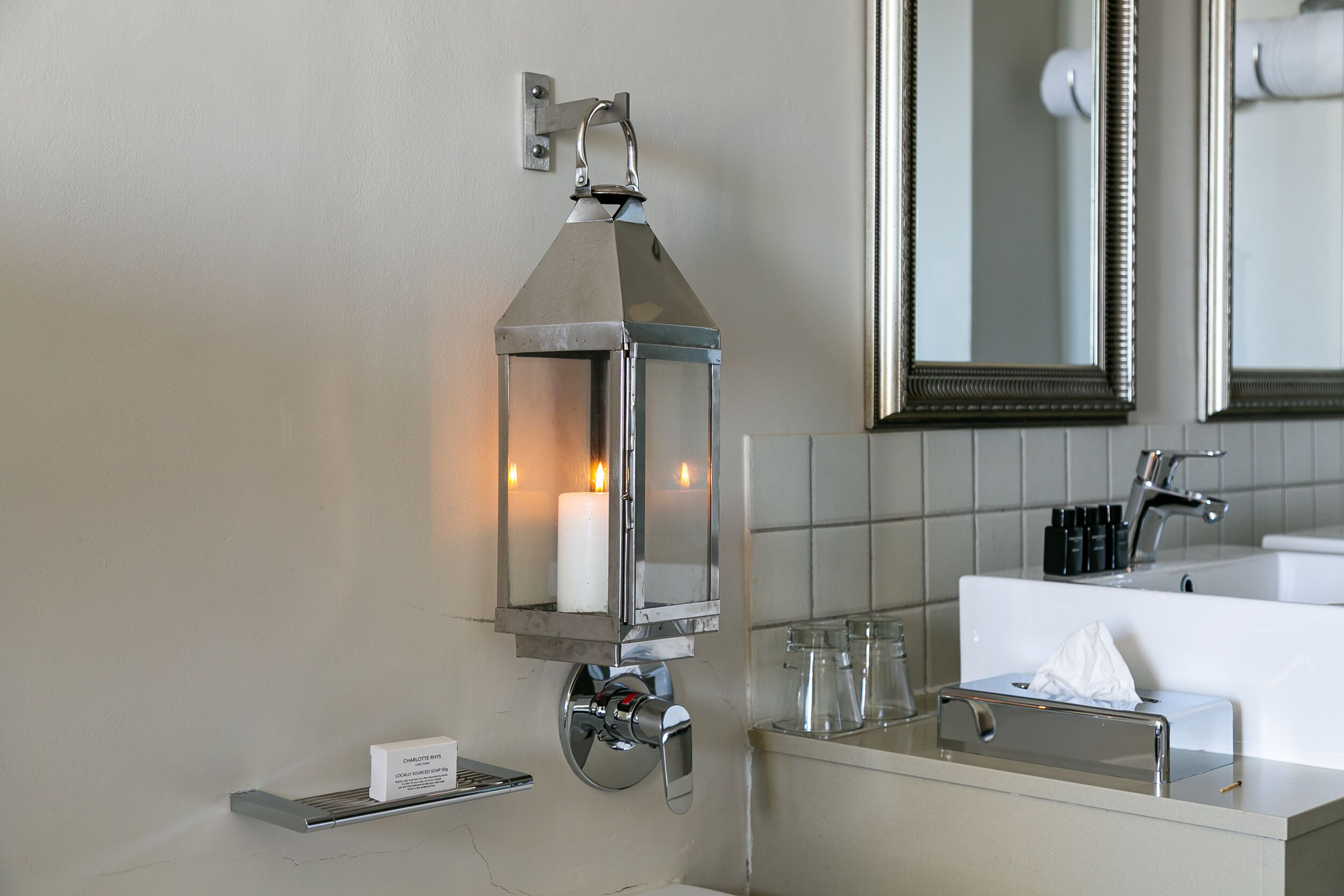 Un baño con una linterna de vela en la pared, un lavabo y un espejo.