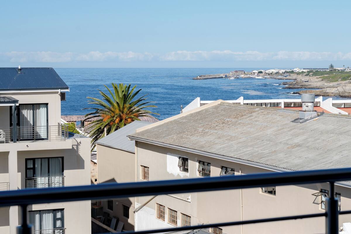 Um edifício costeiro com vista para o mar, uma palmeira e um parapeito de varanda.
