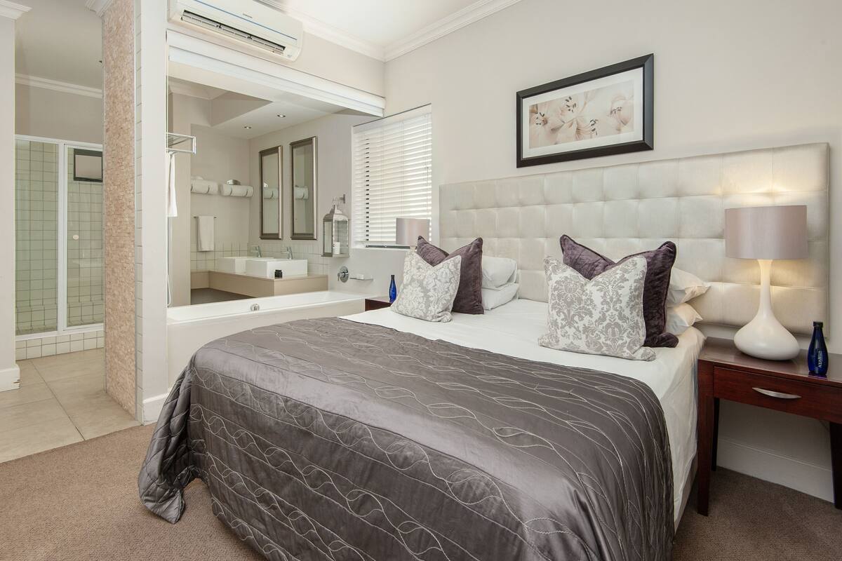 Quarto de hotel com uma cama grande, área de estar, banheira e chuveiro.