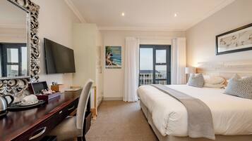 Habitación de hotel con una cama grande, un escritorio con televisor de pantalla plana, un espejo amplio y una ventana con cortinas.