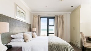 Habitación de hotel con cama, escritorio, silla y vista al mar.