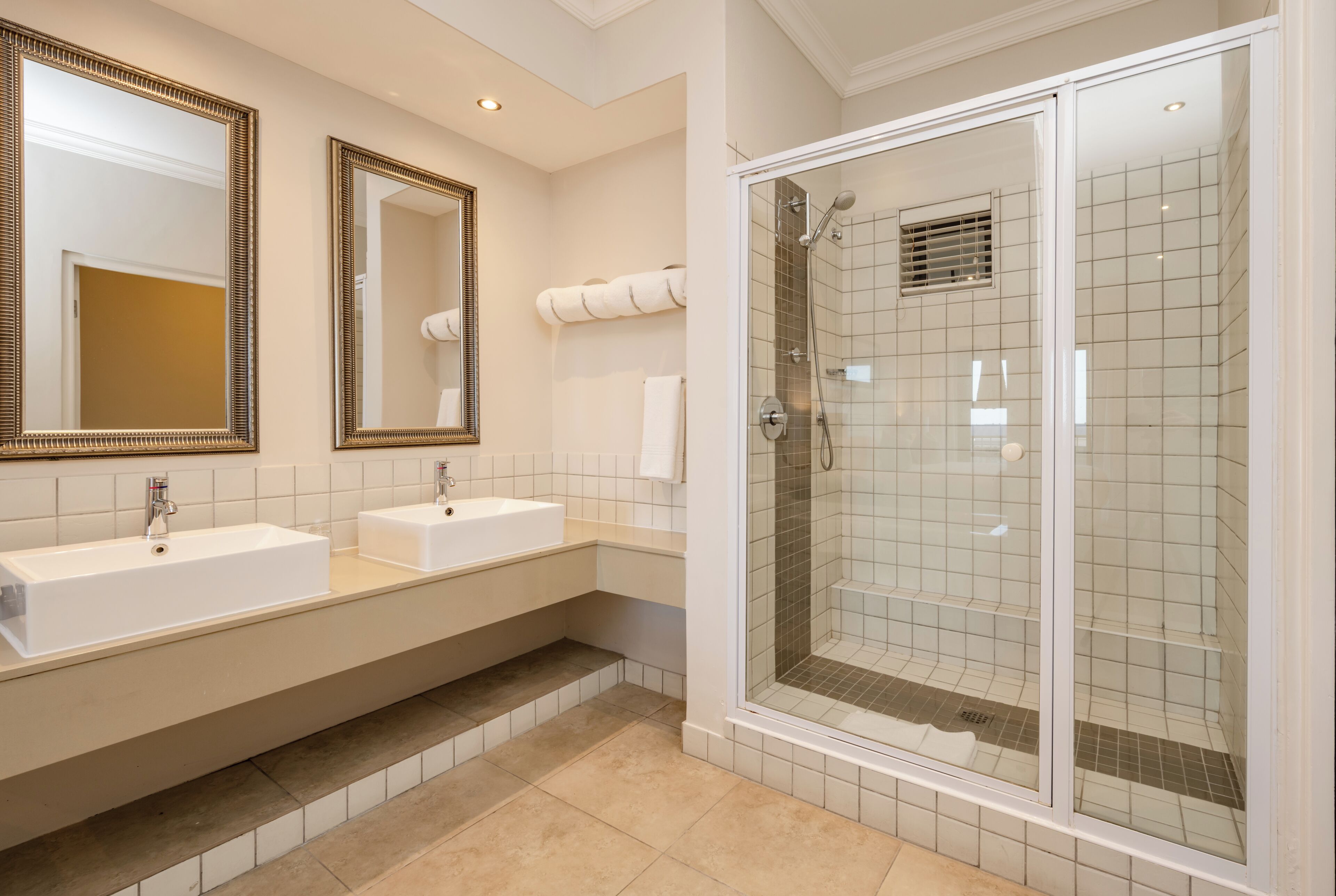Un bagno moderno con due lavandini, una cabina doccia in vetro e ampi specchi.