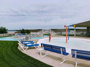A pool area with lounge chairs and a water play structure.