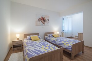 A bedroom with two beds, a nightstand, a lamp, a painting on the wall, and a window with curtains. - Apartment with big terrace in nature perfect for a relaxing holiday (Pula)