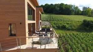 Un bâtiment moderne en bois doté d’un balcon donnant sur un vignoble.