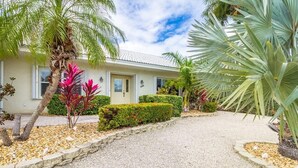 A two-story building with a gravel driveway, palm trees, and a well-maintained garden. - Key Colony Beach Paradise (Key Colony Beach)