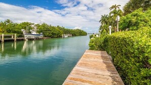 A wooden dock extending into calm water, surrounded by lush greenery and a clear sky. - Key Colony Beach Paradise (Key Colony Beach)