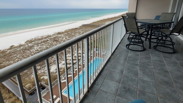 Un balcon avec vue sur une plage et une piscine.