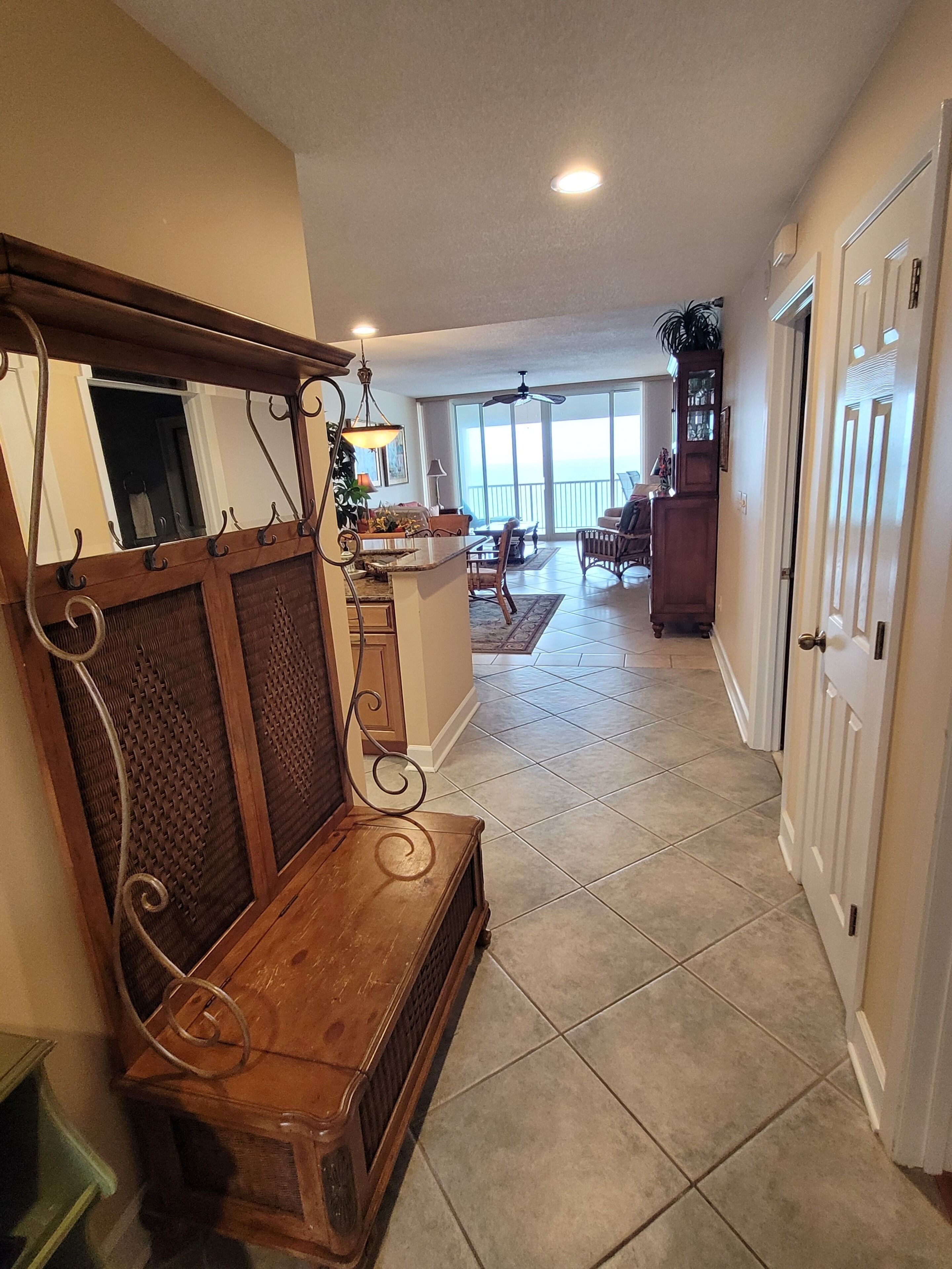 A spacious living area with a wooden bench, a dining table, and a view of the outdoors through large windows.