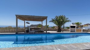 Ein Swimmingpool mit einer Pergola, Gartenmöbeln und Meerblick.