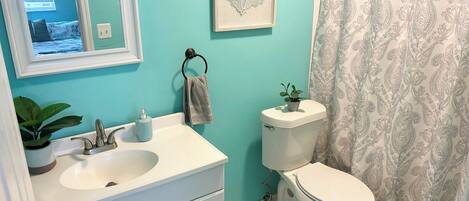 A bathroom with a sink, toilet, and a framed artwork on the wall.