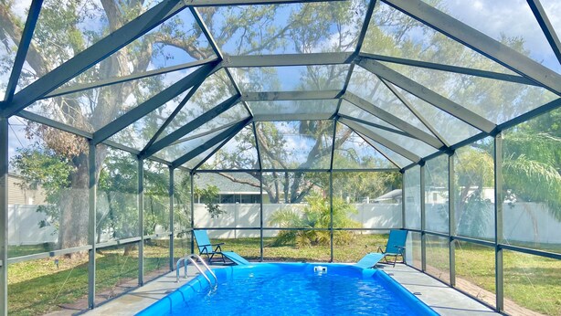 Une piscine couverte offrant une vue dégagée sur les arbres environnants et une maison en arrière-plan.