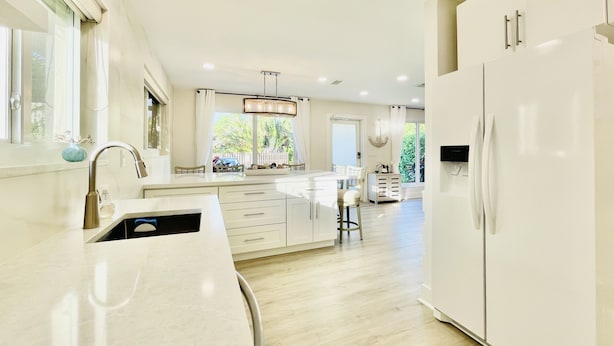 Una cocina moderna con armarios blancos, una isla central y un refrigerador grande.