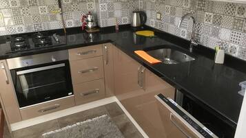 A kitchen with a stove, oven, sink, and patterned backsplash.