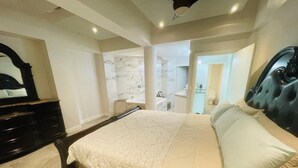 Ein Schlafzimmer mit einem großen Bett, einem dunklen Kopfteil, einem Spiegel und einer Marmorwand.
