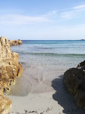 A beach with clear water, sandy shore, and rocky formations.
