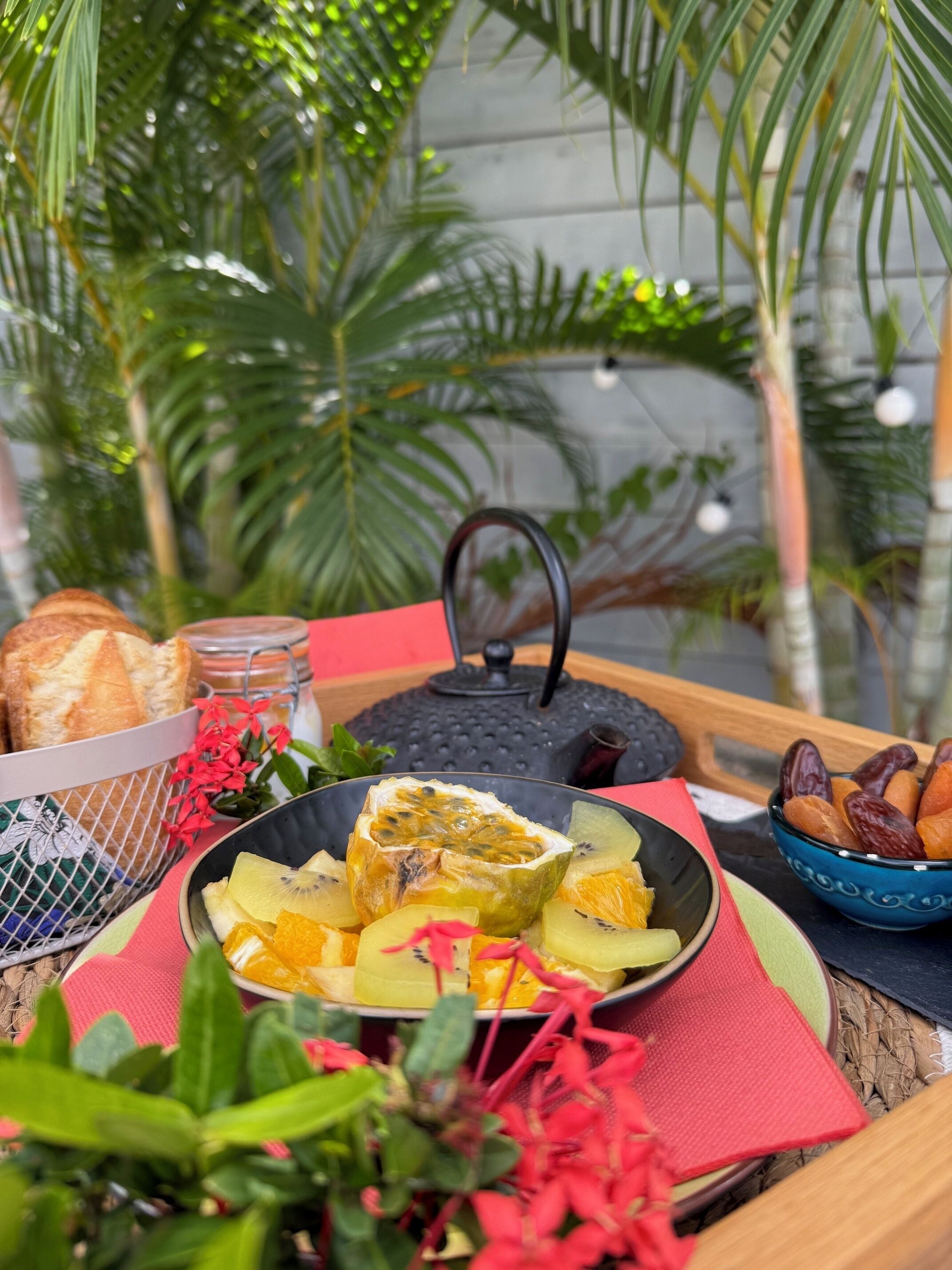 Uma mesa com uma bandeja de frutas, pão e um bule de chá.
