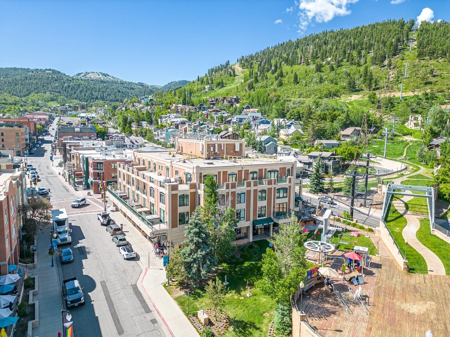 A town with a central building featuring a large sign, surrounded by streets and parked cars.