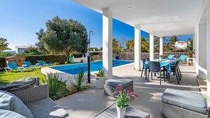 A covered outdoor area with a pool, lounge chairs, and a dining table. - Villa Abril - modern villa only 400 mts from beach (Binisafua)