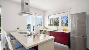 A modern kitchen with a large island, stainless steel appliances, and a view of the outdoors. - Villa Abril - modern villa only 400 mts from beach (Binisafua)