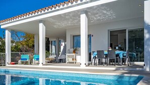 A covered outdoor area with a pool, lounge chairs, and a table with chairs. - Villa Abril - modern villa only 400 mts from beach (Binisafua)