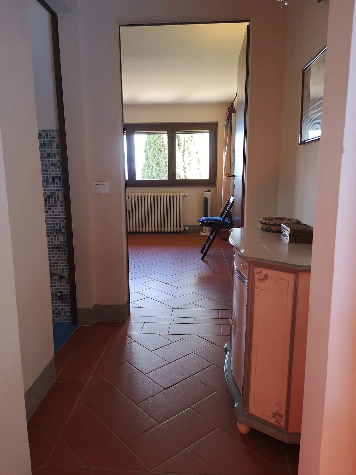 Un pasillo con un radiador, una ventana y una puerta que da a otra habitación.