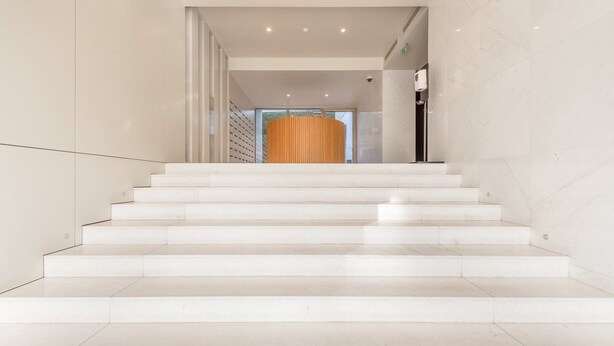 Una escalera conduce a una habitación con un ventanal grande y una puerta con panel de madera.