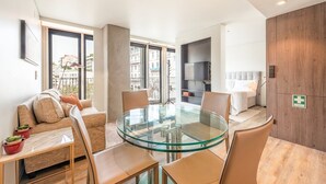 Una sala de estar moderna con una mesa de comedor de vidrio, un sofá y un televisor montado en la pared.