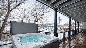 Un bain à remous sur une terrasse en bois, avec vue sur un paysage enneigé.