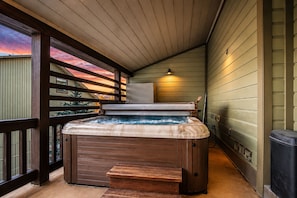 A hot tub on a wooden deck with a view of the sunset.