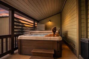 A hot tub on a wooden deck with a view of the sunset.