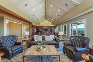A spacious living area with a high ceiling, a fireplace, and a view of the outdoors.