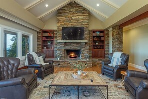 A cozy living room with leather sofas, a stone fireplace, and a flat-screen TV above it.