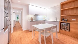 Eine moderne Küche mit weißen Schränken, Holzboden und einem eingebauten Weinkühlschrank.