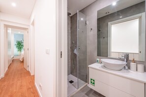 A modern bathroom with a large mirror, a white sink, and a shower area.