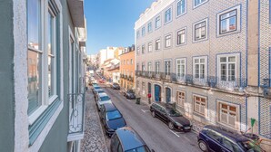 A narrow street lined with multi-story buildings featuring traditional Portuguese tile facades and balconies.