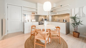 A modern kitchen with white cabinetry, a round dining table, and wooden chairs.