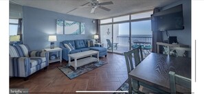 Relax in this stylish living room with a comfortable sofa, dining table, and ocean views from the balcony.