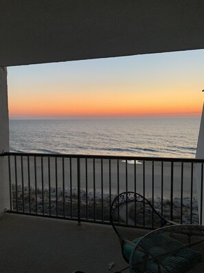Enjoy the ocean view from this balcony with a single chair and metal railing.