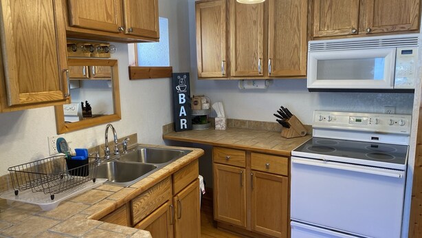 A kitchen with wooden cabinets, a stainless steel sink, a microwave, and a stove.