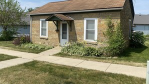 A single-story house with a brick exterior, a front porch, and a small garden.