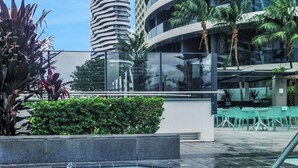 A swimming pool with a water fountain, surrounded by greenery and modern buildings. - Stunning Ocean Views Oracle Level 30 Parking (Broadbeach)