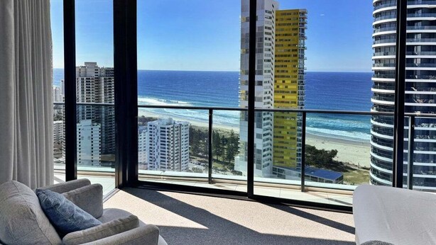 A modern living room with a large balcony overlooking a beach and ocean. - Stunning Ocean Views Oracle Level 30 Parking (Broadbeach)